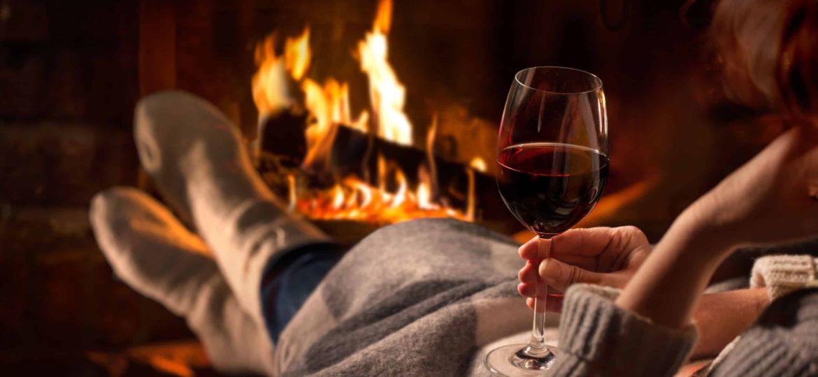 Woman resting with wine glass near fireplace