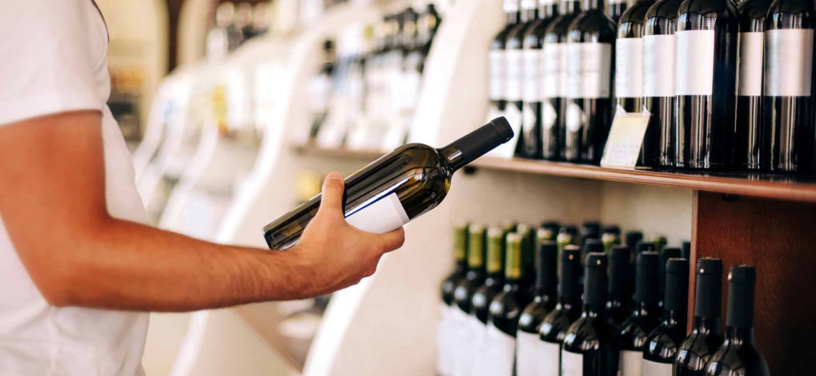 Crop man choosing wine in shop